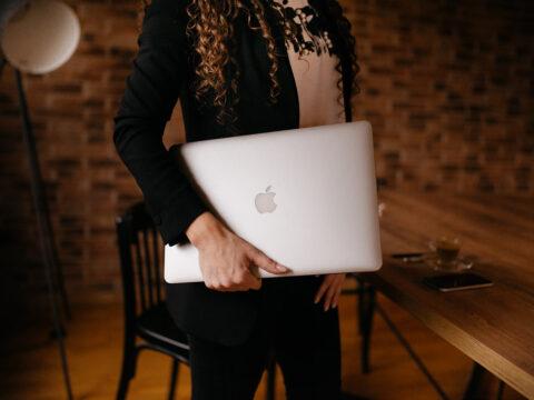 A young business woman holding Macbook in his home office.