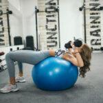 Young Woman exercising with a fit ball in modern gym.