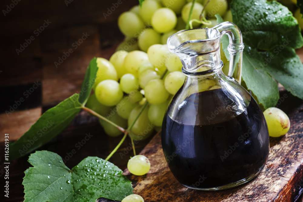 Balsamic vinegar in a glass jug, vintage wooden background, rust